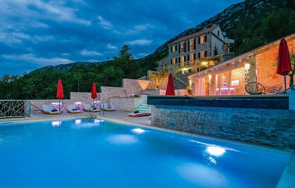 Relax by the serene pool surrounded by lush greenery and hills.