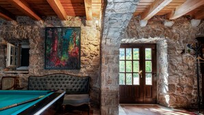 A rustic room with a pool table, a large abstract painting, and a stone wall.