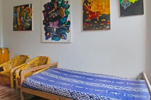 A room with a bed, two wicker chairs, and three artworks on the wall. - Hotel O Bale Datu Homestay Near Lapangan Bulutangkis By'u Badminton (Senggigi)