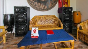 A room with a sofa, two speakers, a drum, and a book on a table. - Hotel O Bale Datu Homestay Near Lapangan Bulutangkis By'u Badminton (Senggigi)