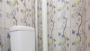 A toilet with a white seat and lid, set against a wall with floral and butterfly patterns. - Hotel O Bale Datu Homestay Near Lapangan Bulutangkis By'u Badminton (Senggigi)