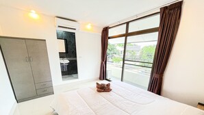 A hotel room with a large bed, a wardrobe, a bathroom with a sink, and a view of the outside.