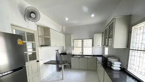 A modern kitchen with white cabinets, a stainless steel refrigerator, a sink, and a window with decorative bars.