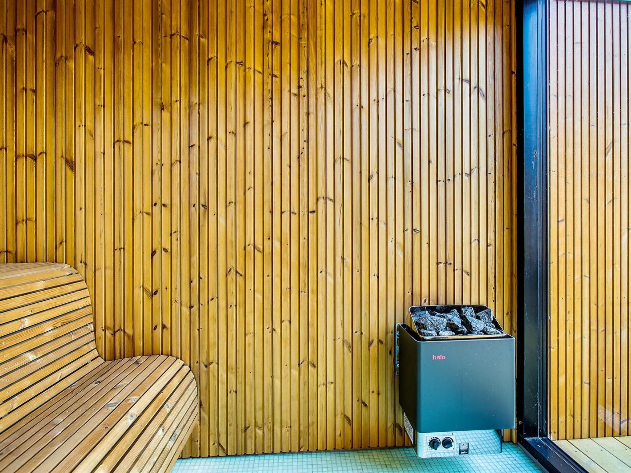 Une pièce en bois avec un banc et un appareil de sauna portant l’inscription « helo ».
