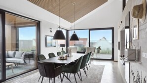 A modern dining area with a large table, black chairs, and pendant lights.
