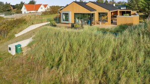 A modern house with a large glass facade, a wooden exterior, and a surrounding grassy area.