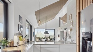 A modern kitchen with a large island, pendant lighting, and a built-in refrigerator.