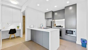 Una cocina moderna con armarios grises, una encimera blanca y un microondas integrado.