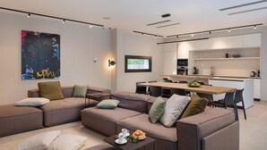 A modern living room with a sectional sofa, a coffee table, and a dining area with a wooden table and chairs.
