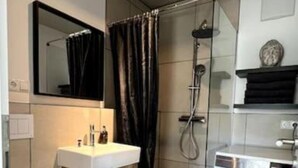 A modern bathroom with a toilet, sink, shower, and washing machine. - M Apartment: Design Apartment Loft (Landau in der Pfalz)
