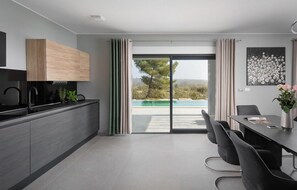 A modern kitchen with a built-in oven and a dining area with a table and chairs.