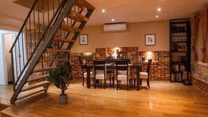 A dining area with a brick wall, a wooden staircase, and a bookshelf.