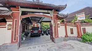 A traditional gate with a sign for ASTRI Home Stay, leading to a covered pathway with parked cars and motorcycles. - Hotel O Astri Homestay (Mataram)