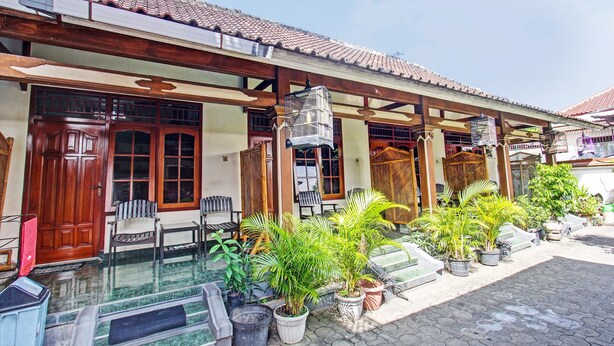 A traditional building with a tiled roof, wooden doors, and a covered outdoor area with potted plants and seating. - Hotel O Astri Homestay (Mataram)