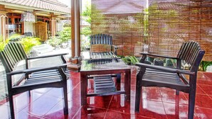 A patio area with two wooden chairs and a table, surrounded by a bamboo fence and potted plants. - Hotel O Astri Homestay (Mataram)
