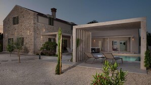 Una casa moderna de piedra con piscina, zona de estar exterior y jardín bien cuidado.