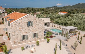 A stone building with a pool, surrounded by a landscaped garden and a view of the countryside. - Beautiful home in Ugljan with sauna (Ugljan)