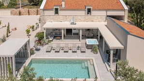 Una casa moderna con fachada de piedra, piscina y mobiliario de exterior.