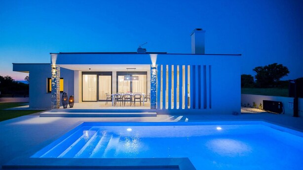 Una casa moderna con piscina, zona pranzo e garage.