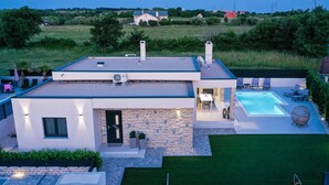Una casa moderna con piscina, facciata in pietra e prato curato.