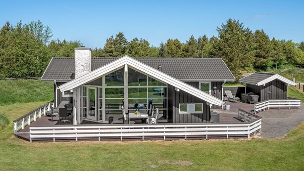 Une maison moderne dotée d’une grande terrasse, d’un patio couvert et d’un garage.