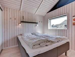 A bedroom with a bed, wooden walls, a window, and a shelf with a lamp. - "Domna" - 800m from the sea by Interhome (Blåvand)