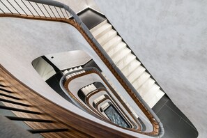 Un escalier en colimaçon avec une rampe en bois et une vue sur les niveaux inférieurs.