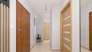 Ein Flur mit Holztüren, einem kleinen Tisch mit Topfpflanze und einem Lichtschalter an der Wand.