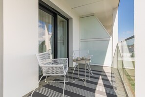 Relax in style with a modern balcony retreat, featuring a wicker chair and small table for a peaceful escape.
