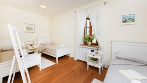 Un dormitorio bien iluminado con cama, mesitas de noche, cómoda y ventana con cortinas.
