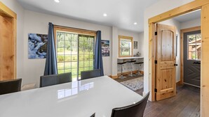 Un espace repas comprenant une grande table, des chaises et une vue sur l’extérieur.