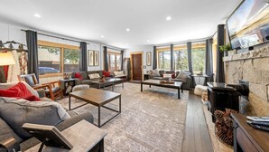 Un salon spacieux doté d’une cheminée, de grandes fenêtres et d’un coin salon confortable.