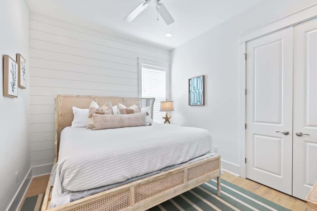 Une chambre à coucher avec un lit, un ventilateur de plafond, une porte et un mur orné d’un tableau encadré.