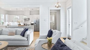 Een moderne woonkamer met een bank, salontafel en een keuken op de achtergrond.