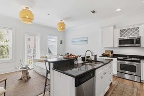 A modern kitchen with white cabinetry, a central island, stainless steel appliances, and pendant lighting.