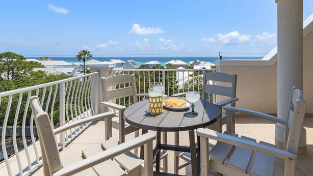 A balcony with a table, chairs, and a view of the ocean. - Ocean Views + Walk to Beach + Golf Cart Included! (Santa Rosa Beach)