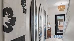 A hallway with framed artwork, a door leading to a balcony, and a hanging light fixture. - Gulf Views | Rooftop Patio | Heated Pool (Santa Rosa Beach)