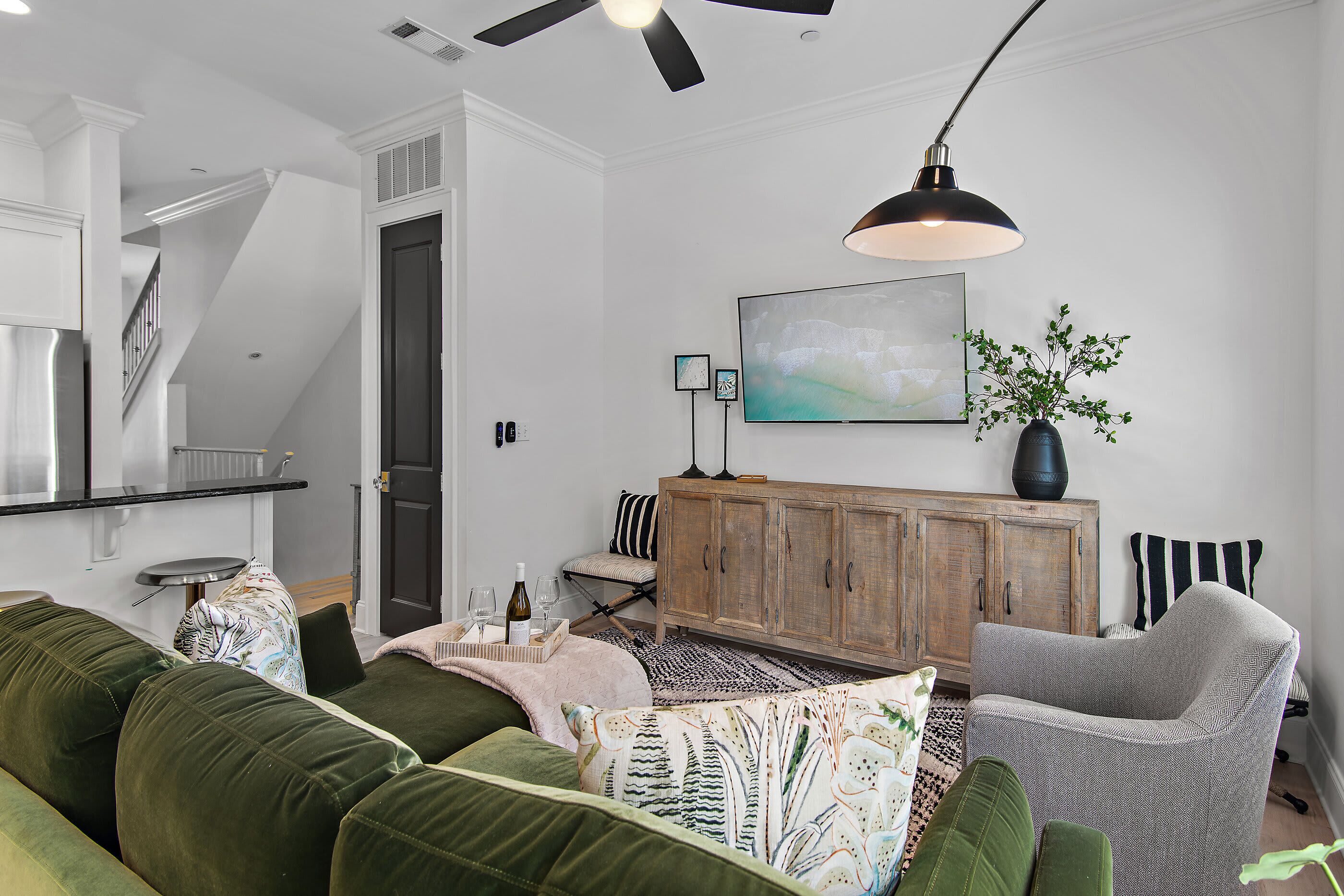 Ein modernes Wohnzimmer mit einem grünen Sofa, einem grauen Sessel und einer Holzkommode.