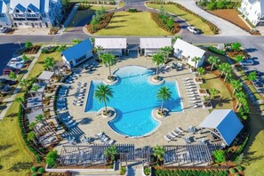 Vista aérea de un resort con una piscina central rodeada de zonas de descanso y palmeras.