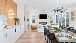 A modern kitchen with white cabinets, a wooden herringbone wall, and a dining area with a large table set for six. - Gulf View Estate | Private Pool | Walk to Beach (Inlet Beach)
