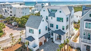 A coastal residential area with modern white houses, a paved driveway, and a view of the ocean. - Gulf View Estate | Private Pool | Walk to Beach (Inlet Beach)