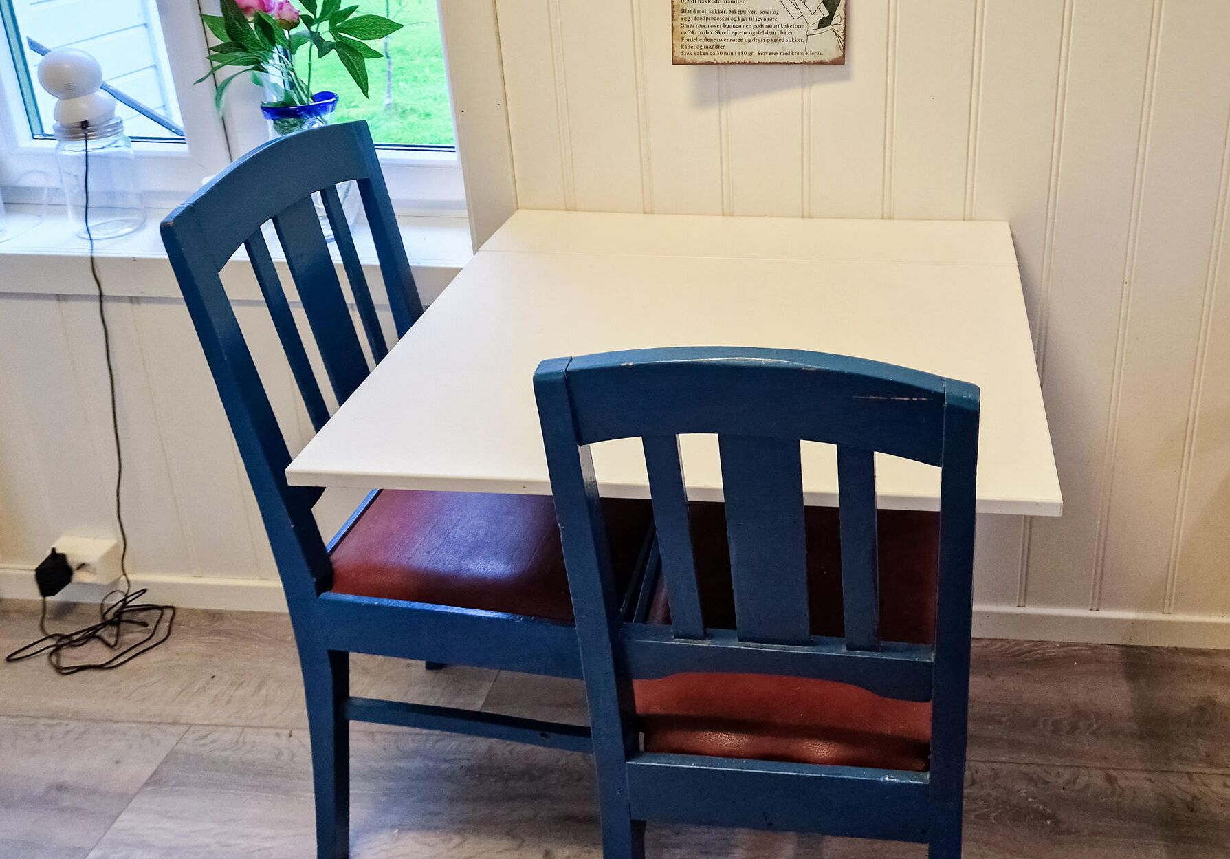 A dining table with a white tabletop and a blue chair with a leather seat.