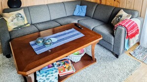 A living room with a grey sofa, a wooden coffee table, and a basket with books.
