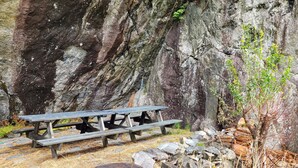 A rustic picnic table set against a rocky cliff backdrop.