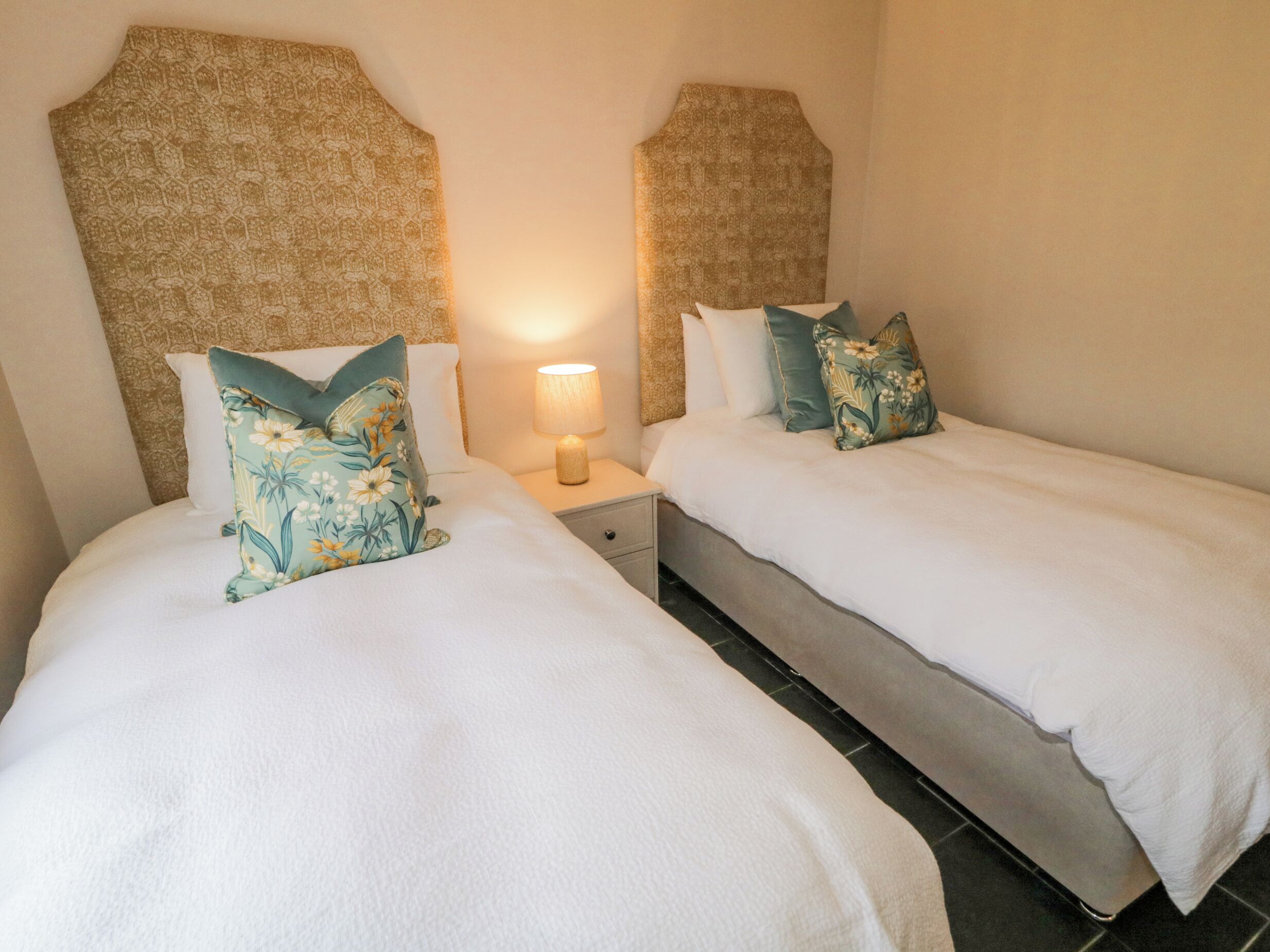 A double room with two beds, each with floral pillows and a headboard.