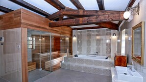 Une salle de bain moderne avec un sauna à parois de verre, une baignoire sur pied et un grand miroir.