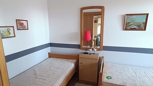 A small, compact room with two single beds, a wooden desk, a mirror, and a small cabinet. - Ferienwohnung Sielluft (Dornum)