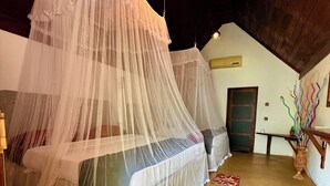A bedroom with two beds covered by white canopy beds, a wooden ceiling, and a single hanging light fixture. - Maika safari (Udawalawa)