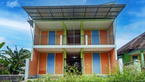 A two-story building with a balcony on the upper floor, surrounded by greenery. - Hotel O Kemangi Asri Kost (Banyuwangi)