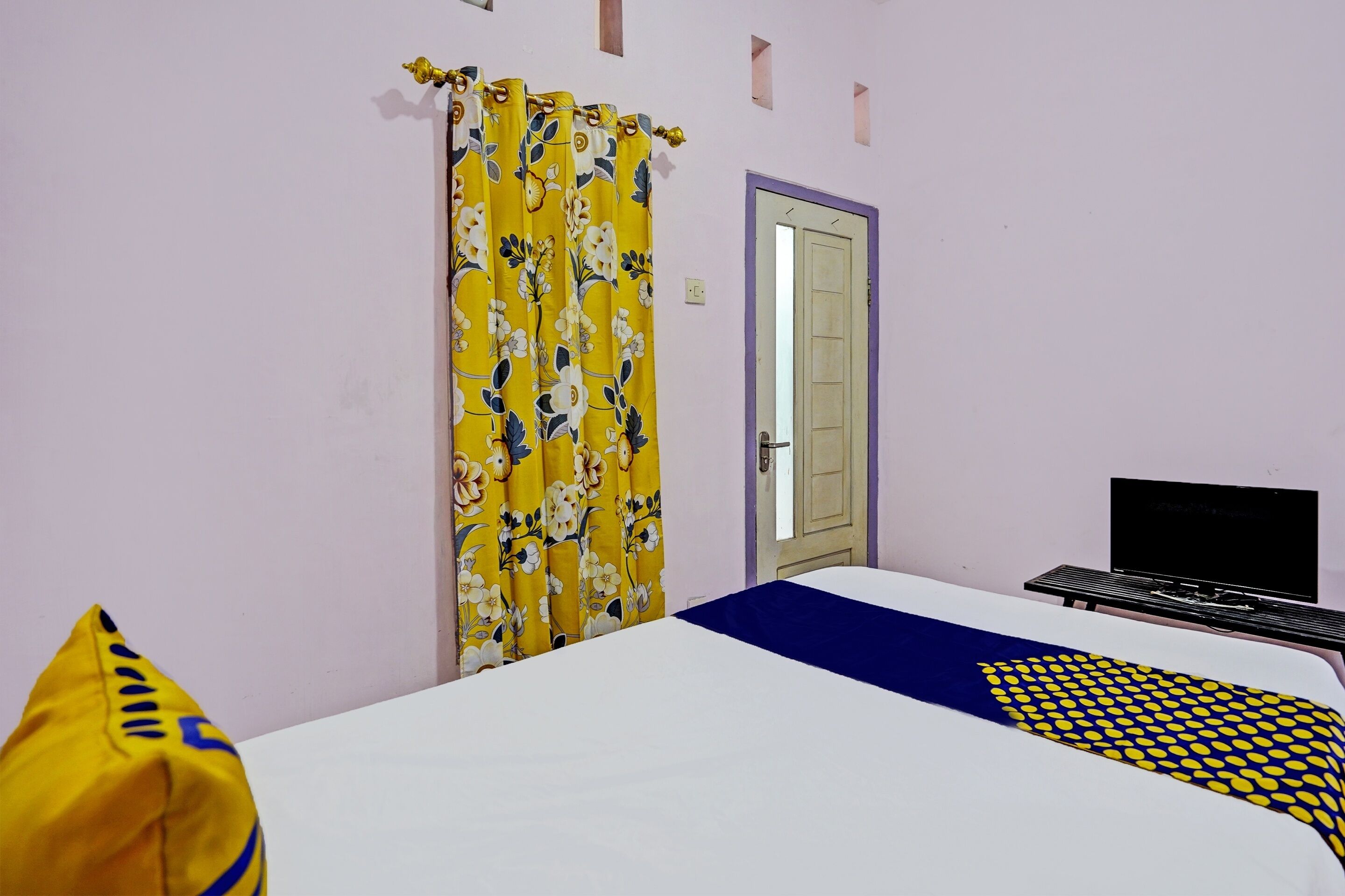 Um quarto com cama, televisão e porta com espelho.